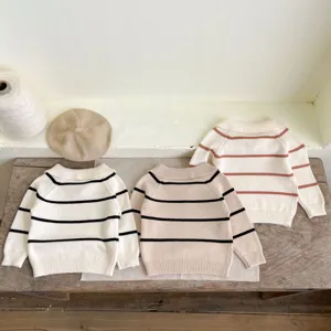 Detailed view of cozy infant striped knit sweaters with lapel collars on wooden background.