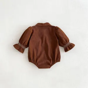 Close-up back view of infant brown corduroy baby romper with cute frill embroidered sleeves.