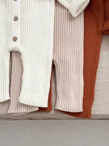 Detailansicht des gerippten Baby-Stramplers aus Strick mit weicher Textur und Holzknöpfen.