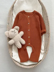 Baby Strick Langarm-Strampler in Terrakotta mit Holzknöpfen für süße Babys im Frühling.