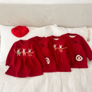 Detailed view of cute baby girls red plush-lined knitted dress with hand-embroidered rabbit design.