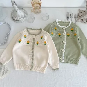 Detailed view of cute baby knitted cardigan featuring floral embroidery and ruffle trim.