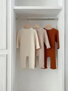 Detailansicht von Babystrick-Overalls in Creme, Beige und Rost, weich und bequem für Babys.