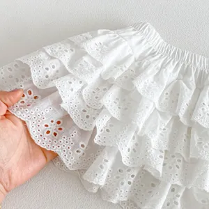 Detail shot of white cotton eyelet lace ruffled baby skirt pants showing soft fabric texture.