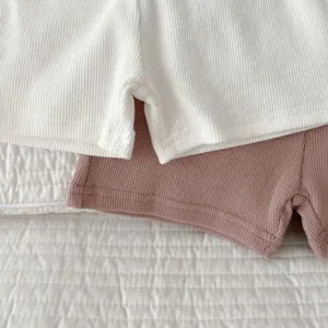 Detailed shot of baby ribbed cotton shorts in white and mauve, soft texture, close-up view