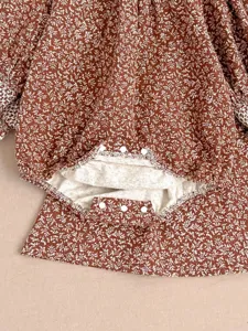 Close-up detail of infant baby girl floral romper showing snap buttons and fine fabric print.