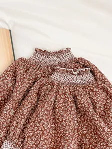 Infant baby girl floral print dress detailed view showing smocked mock neck and cute ruffles.