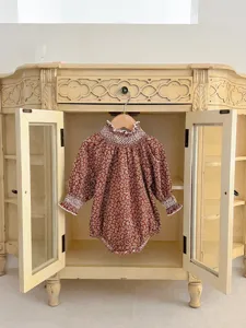 Detailed shot of vintage style floral baby romper with cute smocked ruffles and lace collar.