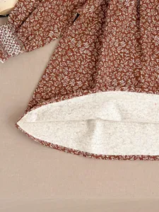 Infant baby girl floral long sleeve dress detail shot, brown cute toddler dress hem fabric.