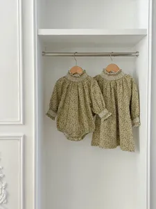 Detail shot of matching baby floral romper and dress featuring ruffled high neck and lace cuffs.