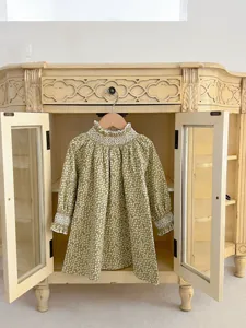 Infant long sleeve floral dress detail shot, hanging inside a vintage wooden cabinet.