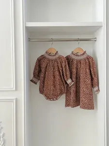 Detailed view of matching floral baby romper and dress with chic white lace ruffles.