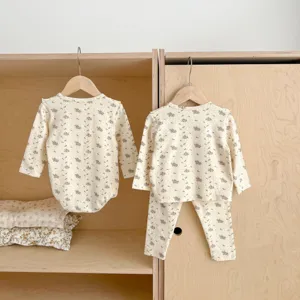 Detail view of infant floral baby girl clothing set hanging in a neat wooden wardrobe display.