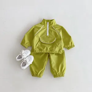 Detalle en primer plano del conjunto de chándal y chaqueta cortavientos verde.