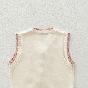 Detail view of cute baby knitted vest, sleeveless sweater with contrast pink trim.