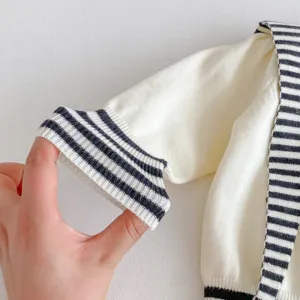 Close-up detail of infant knit cardigan sleeve cuff, black and white striped ribbed knit.