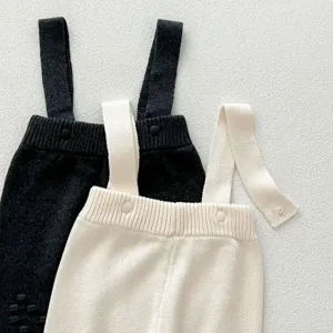 Detailed view of baby knit suspender trousers, soft texture and snap button details close up.