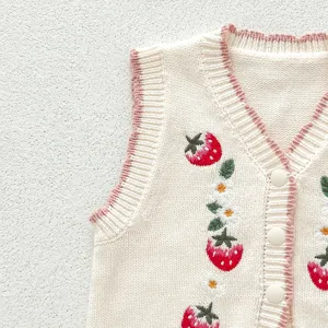 Close-up view of a cream knit baby vest featuring delicate strawberry embroidery and pink trim.