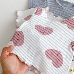 Gros plan détaillé du haut à manches courtes côtelé pour bébé avec joli imprimé cœur rose.