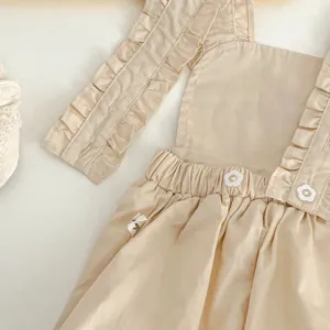 Set top maniche lunghe con volant e abito con bretelle per bambina color albicocca, dettaglio.