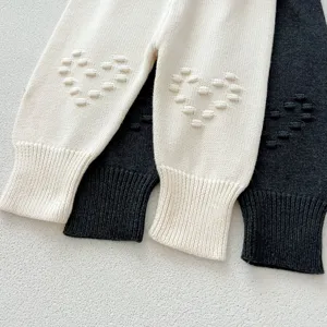 Infant knit leggings detail, cute 3d heart knee design, soft wool texture, close-up view.