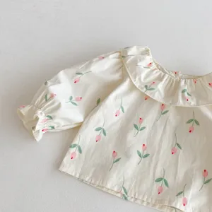 Primo piano camicetta bambina con stampa floreale, colletto volant e maniche a palloncino.