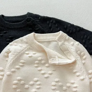 Close up view of infant knit sweater, cute bobble texture and convenient shoulder buttons.