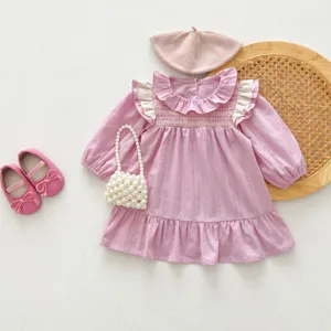 Vista dettagliata di un grazioso abito rosa a maniche lunghe da bambina con volant e accessori.