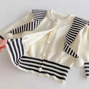 Detailed view of an infant knit cardigan with striped collar and cute pom-pom design.