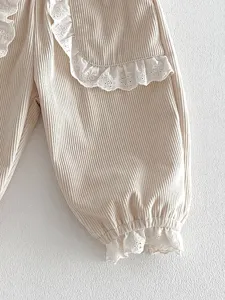 Close-up detail of girls corduroy pants featuring delicate white lace trim and cuffs.