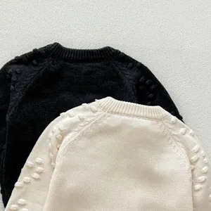 Infant knit sweater detail showcasing soft fabric, round neck and cute textured bobble sleeves.
