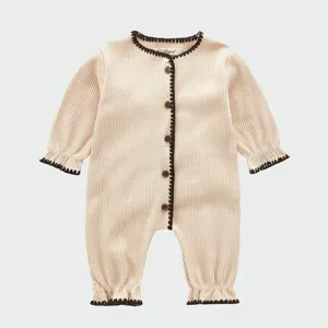 Detail des gerippten Baby-Bodys mit kontrastierender brauner Kante und vorderen Knöpfen.