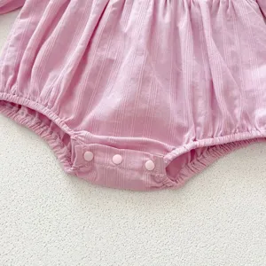 Dettaglio in primo piano della tutina body a coste per neonata rosa con bottoni a pressione.