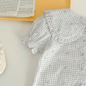 Dettaglio camicetta neonata a quadri e ciliegie, colletto con volant dolce per bambine.