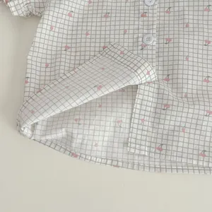 Dettaglio tessuto camicia neonato a quadri stampa ciliegia maniche corte bottoni.