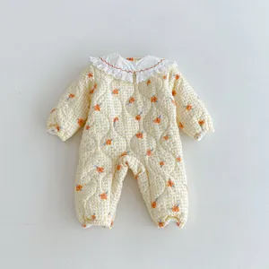 Detailed view of cute baby quilted jumpsuit in yellow with sweet floral print and white lace collar.