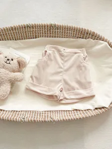 Baby corduroy shorts detail shot, pink solid color infant casual trousers with turn-up cuffs.