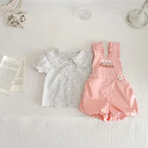 Vista dettagliata di un grazioso set di abbigliamento per neonati con camicetta e pantaloncini.