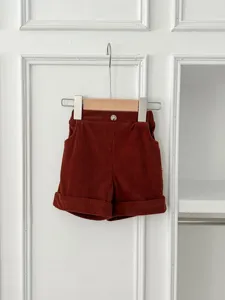 Detail view of brown corduroy baby shorts featuring a single button and rolled cuffs.