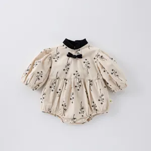 Detailed view of baby girl floral romper, vintage black bow collar, soft fabric design.
