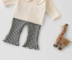Close-up details of toddler girls cotton long sleeve top and black white plaid flare pants set.
