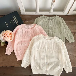 Vue détaillée de jolis cardigans en tricot ajouré pour bébé fille aux doux tons pastel.