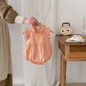 Detail view of infant sleeveless cotton romper in soft peach, featuring delicate ruffle stand collar.