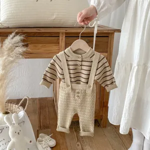 Dettaglio del set maglione e salopette in maglia per neonati con righe carine e bottoni in legno naturali.