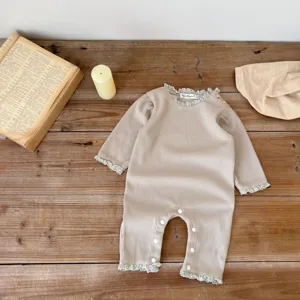 Detailaufnahme des Baby Waffel-Rompers mit Spitzenkragen auf rustikalem Holztisch.