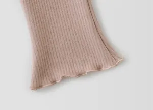 Ribbed knit flare pants hem detail close-up, soft cotton blend fabric with cute lettuce edge.