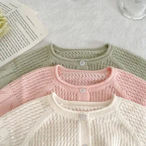 Détail de gros plan cardigan en tricot ajouré pour bébé fille, couleur unie respirante.