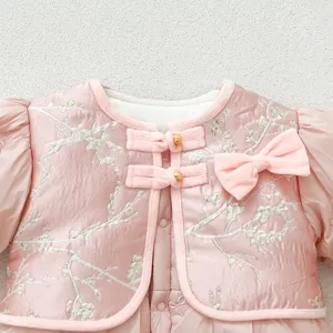 Close-up of pink baby winter padded romper front chest embroidery and traditional frog buttons.