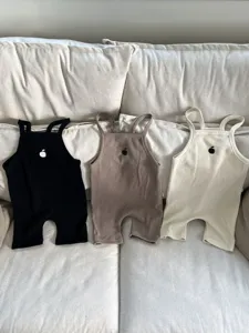 Gedetailleerd overzicht van wafelbreisel baby romperpakjes met appelborduurwerk in drie.