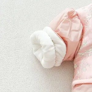 Close-up of baby winter coat sleeve cuff with soft white fleece lining and delicate embroidery.
